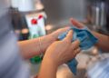 Detailed image of two people cleaning using a blue cloth indoors. Perfect for hygiene concepts.