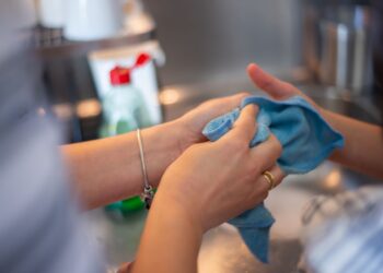 Detailed image of two people cleaning using a blue cloth indoors. Perfect for hygiene concepts.