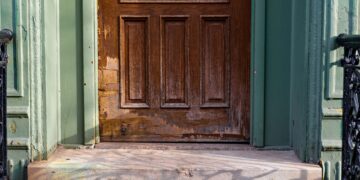 A close-up view of an old wooden door with peeling paint and vintage charm.