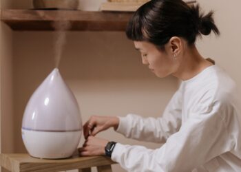 A woman adjusts a humidifier indoors, promoting relaxation and air quality.