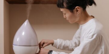 A woman adjusts a humidifier indoors, promoting relaxation and air quality.