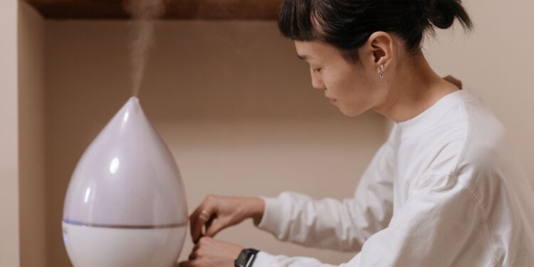 A woman adjusts a humidifier indoors, promoting relaxation and air quality.