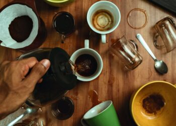 Dynamic overhead photo of coffee being poured into mugs with spills and stained cups.
